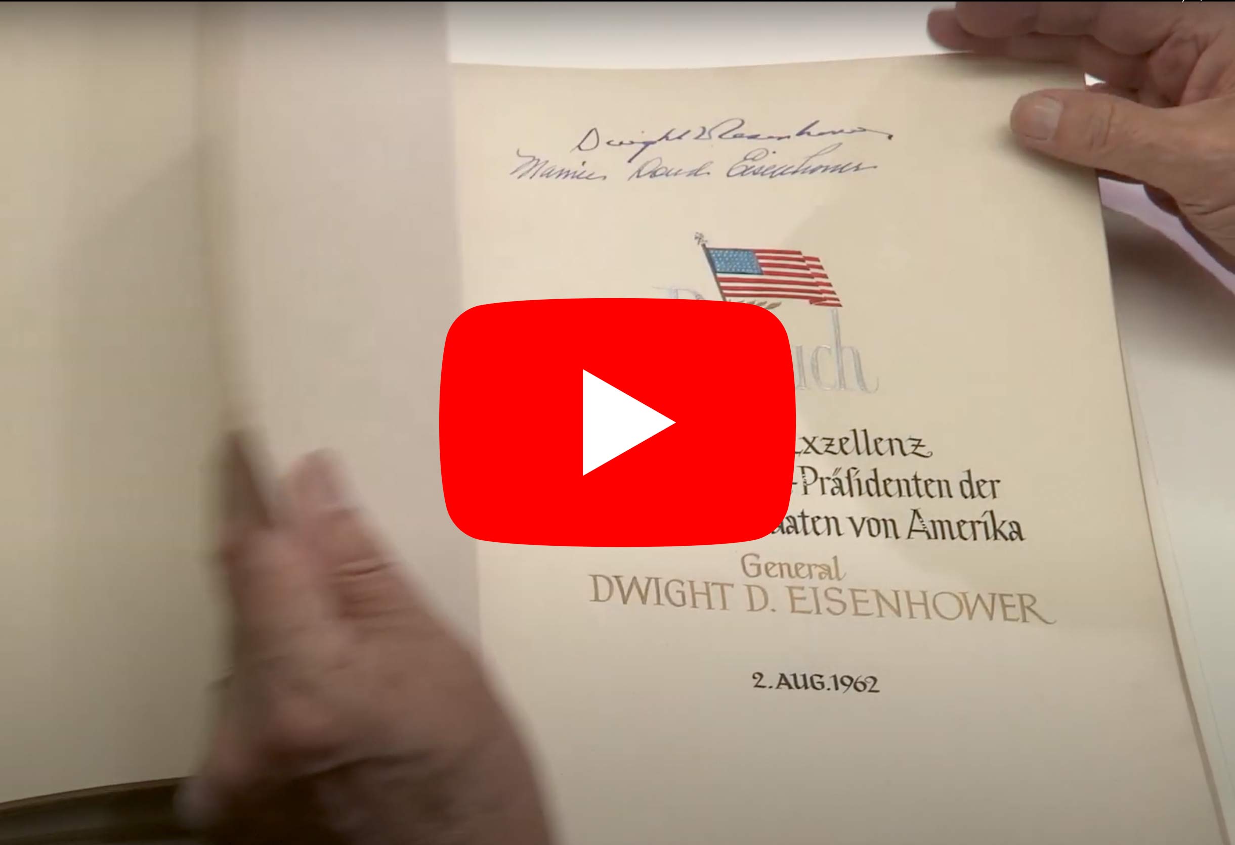 Screenshot aus Video. Hand blättert goldenes Buch der Stadt umn, Eintrag Eisenhower. Roter Youtube-Button