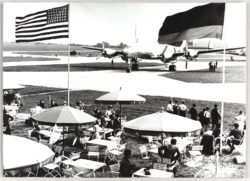 Schwarzweißfotos eines Außenlokals am Flughafen, im Hintergrund Flugzug, oben im Bild  US- und deutsche Flagge