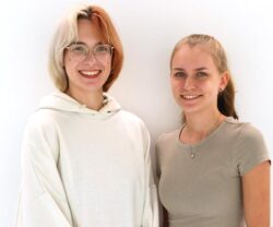 Zwei junge Frauen vor weißem Hintergrund lächeln in die Kamera