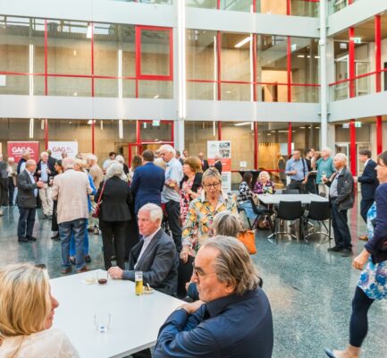 Blick in den verglasten Lichthof des Rathauses, viele Menschen im Gespräch und beim Essen